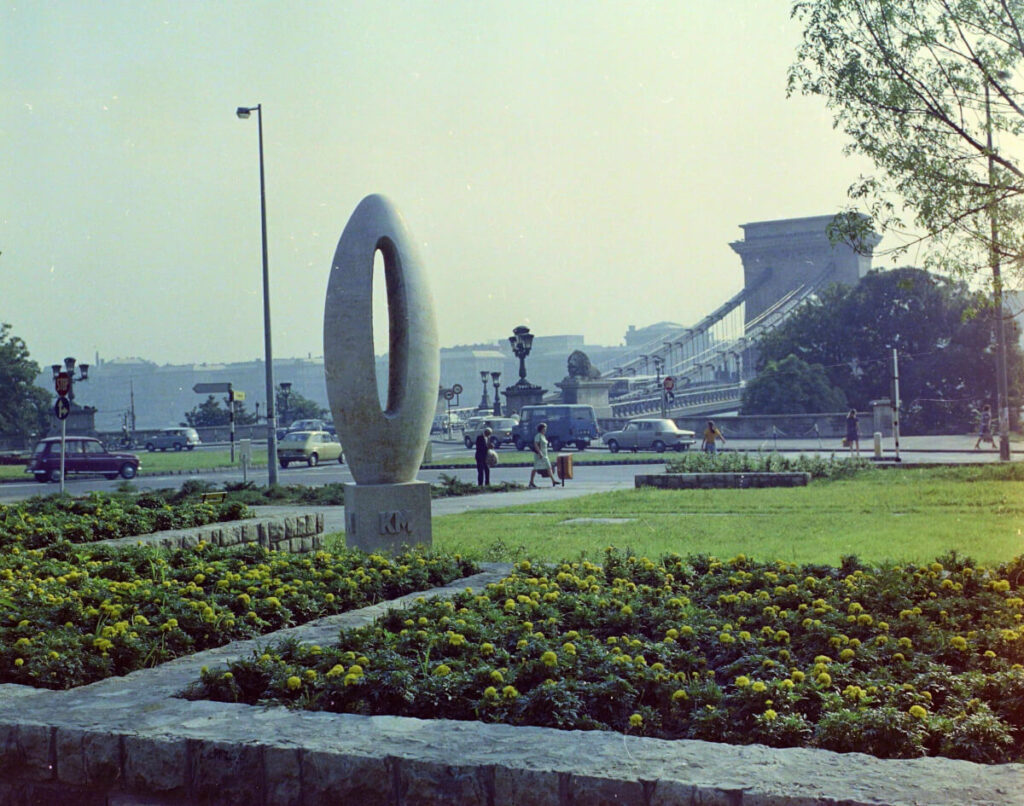 Ungarn, 1975 Budapest I. Clark Ádám Platz, Kilometerstein "0" (Miklós Borsos, 1975.), im Hintergrund die Széchenyi Kettenbrücke.